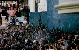 Cascamorras alza su cachiporra mientras es introducido en la fuente de los Caños Dorados