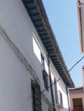 Rehabilitación de una fachada por el Área de Rehabilitación de Baza, casa n° 1 callejón de la Merced. Alero con color inadecuado y solera de balcón encalada, sin dejar a la vista las losetas o maderas en su color original y tradicional.