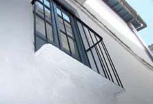 Rehabilitación de una fachada por el Área de Rehabilitación de Baza, casa n° 1 callejón de la Merced. Alero con color inadecuado y solera de balcón encalada, sin dejar a la vista las losetas o maderas en su color original y tradicional.